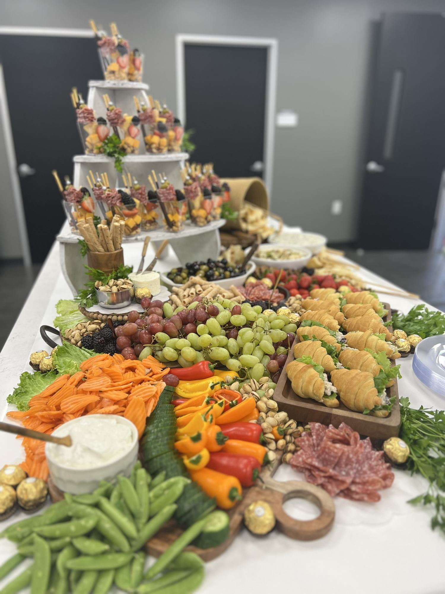 Grand grazing table layered with fruit, cheese, vegetables and skewers