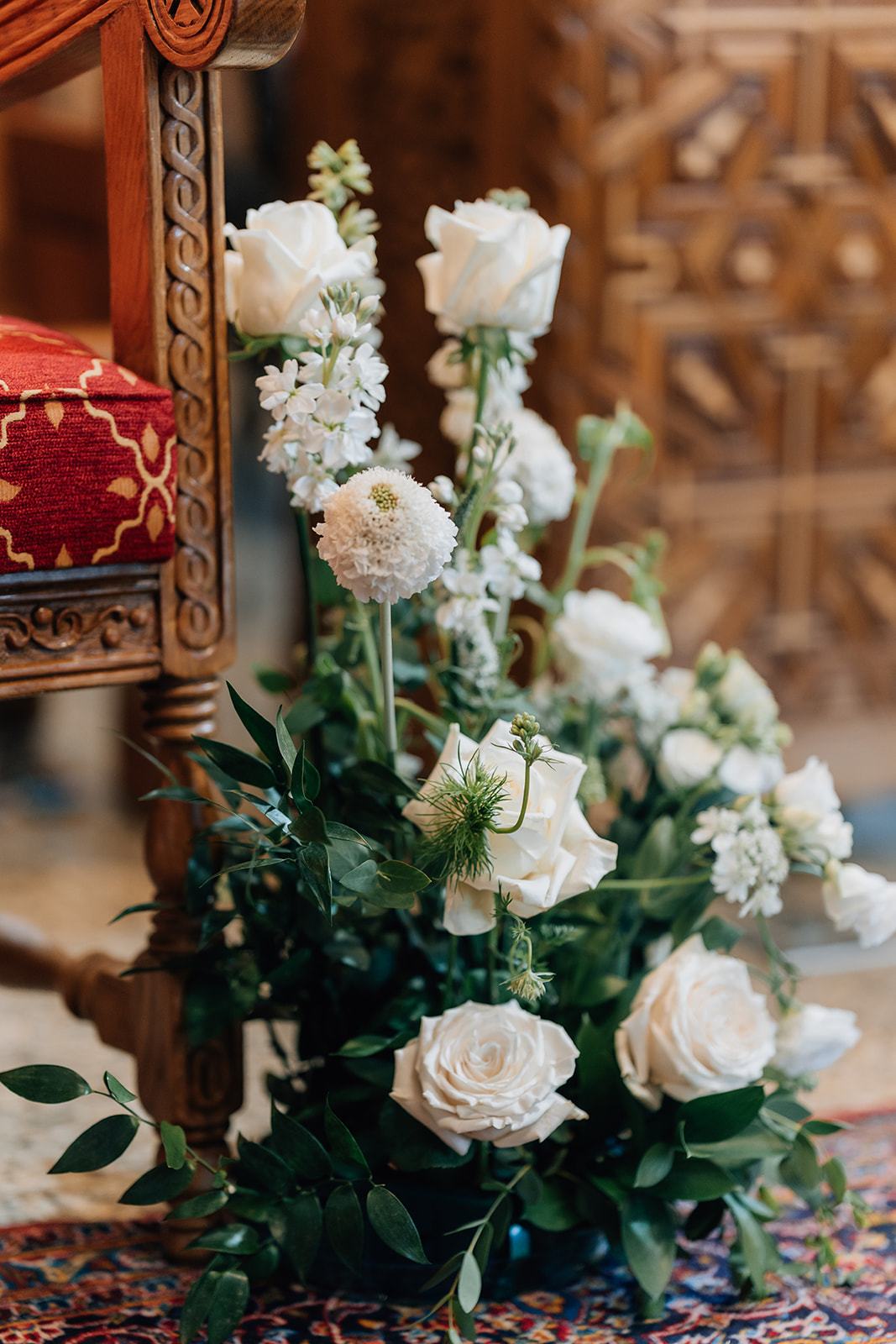 Tall white rose and delphinium arrangement against a carved gold screen