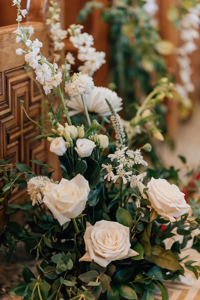 Tall white rose and delphinium arrangement against a carved wall