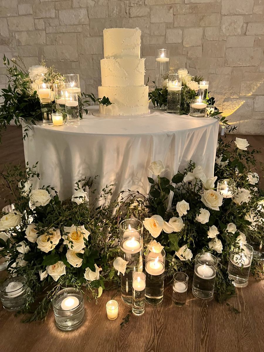 Cake table skirted in white blooms and votives