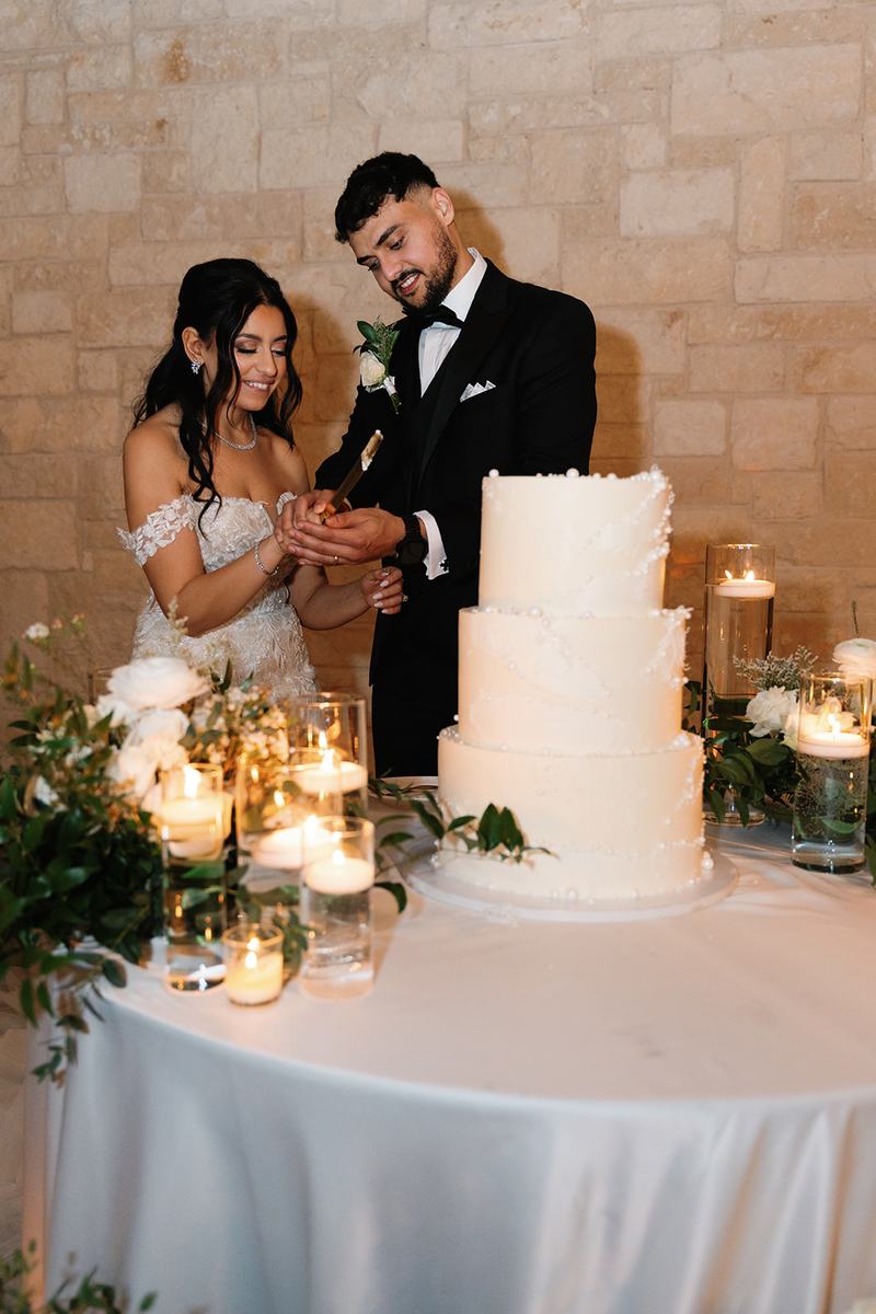 Couple cutting a tiered cake surrounded by candles