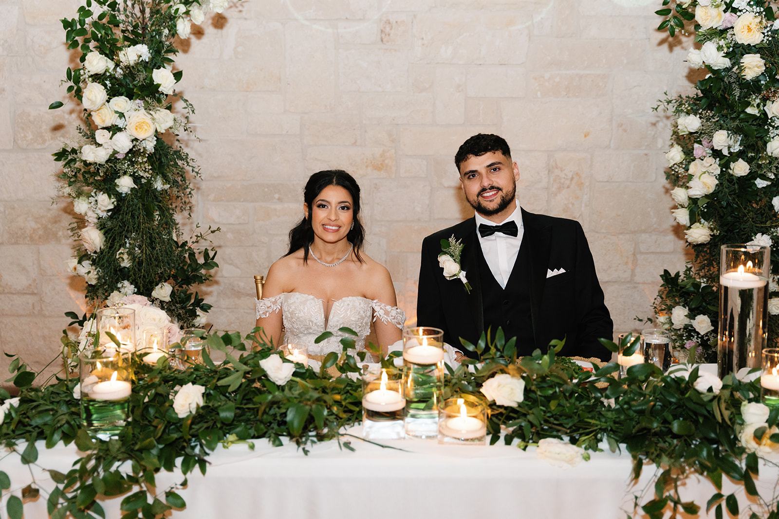 Newlyweds at a garland-draped sweetheart table