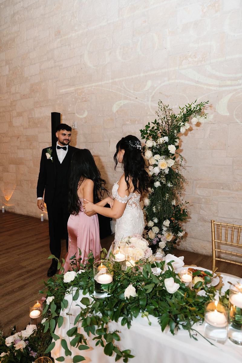 Couple beside a floral installation in a candlelit reception room